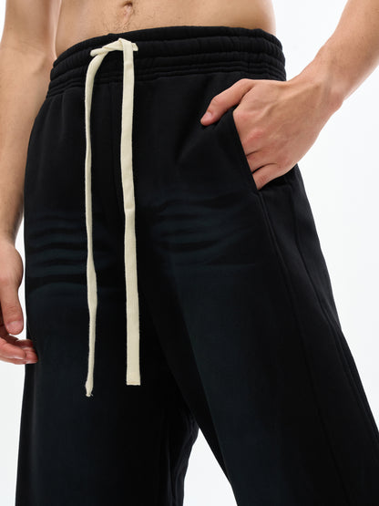 ODMPOD Sunfade Curved Blade fleece sweatpants displayed on a model, featuring a relaxed fit and curved design in soft fleece fabric.